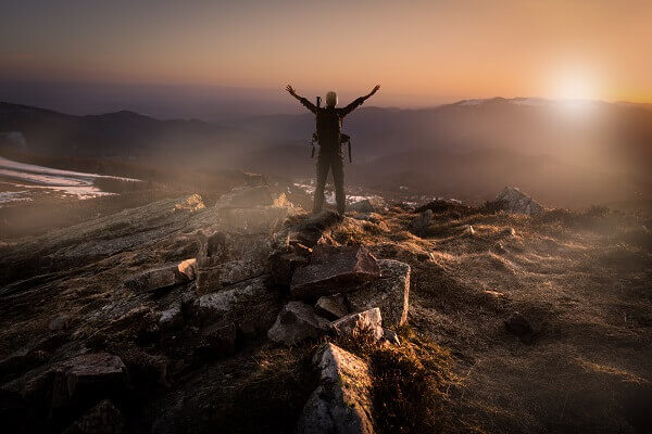 man on top of mountain contemplating retirement